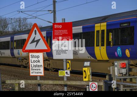 Northern Rail Zug fährt über unbemannte Bahnübergänge (streckenseitige Eisenbahnwarnungen) - Burley in Wharfedale, West Yorkshire, England, Großbritannien. Stockfoto
