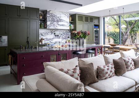 Geräumige Küche mit Auberginen- und olivgrünen Anstrichen im zeitgenössischen Neudesign des Hauses West London. Stockfoto