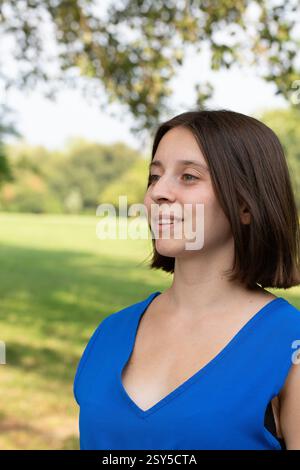 Porträt einer fröhlichen jungen Frau, die einen sonnigen Tag in einem grünen Park genießt Stockfoto