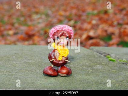 Lustige Kastanienfigur mit rotem Hut und gelbem Schal an der Wand Stockfoto