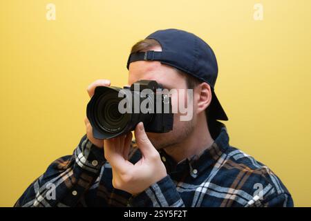 Ein männlicher Fotograf, der gerade fotografiert, auf gelbem Hintergrund. Stockfoto