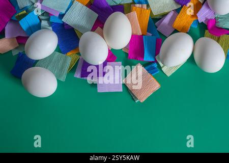 Blick von oben auf hell dekorierte Ostereier auf einem mehrfarbigen Krepppapierhintergrund. Stockfoto