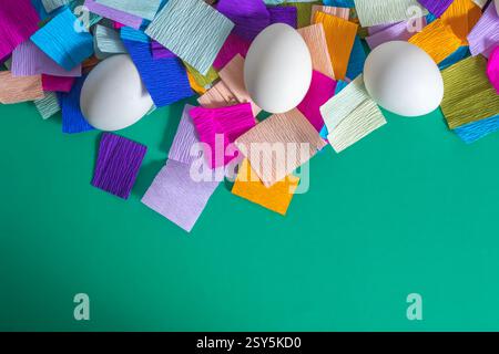 Blick von oben auf hell dekorierte Ostereier auf einem mehrfarbigen Krepppapierhintergrund. Stockfoto