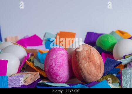 Weiße und farbige Ostereier mit lebendigem Krepppapier auf weißem Hintergrund, symbolisiert die Weihnachtsdekoration und das fest. Stockfoto