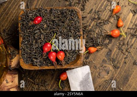 Zutaten für köstlichen Tee mit Rosenfrüchten, Nahaufnahme Hagebuttenfrüchte in rotem und grünem Tee auf dem Tisch während des Kochens Stockfoto