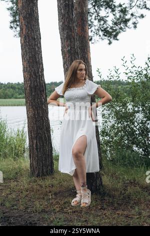 Romantisches Paar, das sich an einem bewölkten Tag in der Nähe eines Sees und eines Waldes küsst und umgibt. Stockfoto