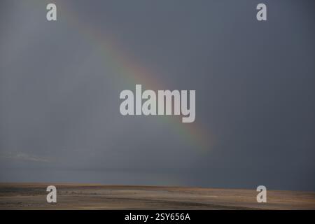 Regenbogen und ein Lichtspiel am bewölkten Himmel an einem regnerischen Tag über Qumran und dem Toten Meer, dem See, seinem Wasser und seinem Ufer. Stockfoto