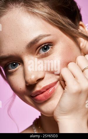 Eine schöne junge Frau posiert spielerisch und zeigt ihre Eleganz vor einem leuchtend rosa Hintergrund. Stockfoto