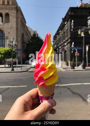 Eis in einem Kegel mit zwei verschiedenen Geschmacksrichtungen in Form einer Welle im Stadtzentrum im Sommer. Hochwertige Fotos Stockfoto