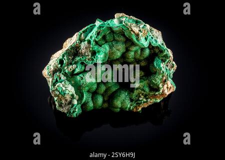 Grüner Felsen mit einem Loch in der Mitte. Er ist glänzend und hat einen Metallic-Look. Es ist auf schwarzem Hintergrund Stockfoto