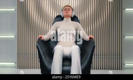 Kaukasische Frau weibliche Gamerin Virtual Reality futuristische Zukunftstechnologie Neon Studio Mädchen Geschäftsfrau auf Stuhl Entspannen Sie sich mit schnurlosen Kopfhörern Stockfoto