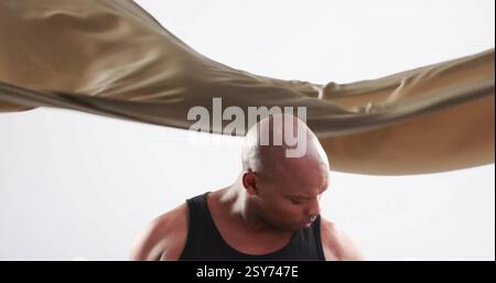 Bild eines fetten afroamerikanischen Mannes, der mit Kurzhanteln über braunem Stoff arbeitet Stockfoto