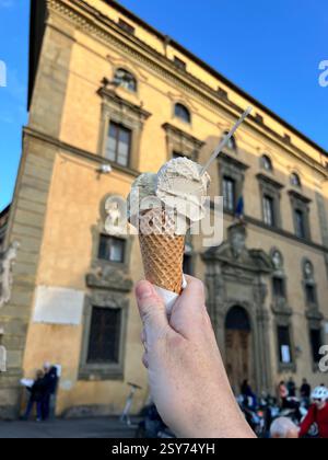 Eine Hand, die einen Eiskegel gegen ein historisches europäisches Gebäude hält Stockfoto