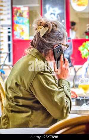 Reife Frau saß am Café-Tisch und telefonierte mit dem Smartphone - Tours, Indre-et-Loire (37), Frankreich. Stockfoto