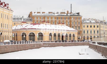 St. Petersburg Straßenfoto mit dem Fluss Moyka in der kalten Jahreszeit. Der runde Marktaufbau steht im Hintergrund Stockfoto