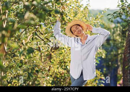 Stehen und posieren. Die junge, fröhliche Frau ist tagsüber im Garten. Stockfoto