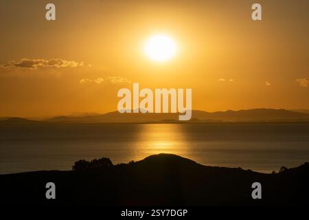 Atemberaubender Sonnenuntergang von der Insel der Sonne über dem Titicacasee mit warmen goldenen Tönen und majestätischer Bergkulisse Stockfoto