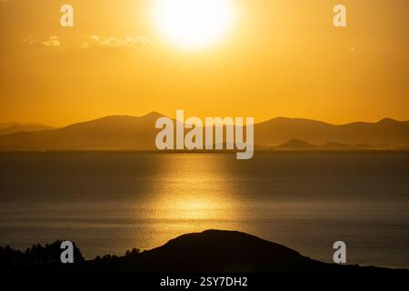 Magischer Sonnenuntergang über dem Titicacasee von der Insel der Sonne, eingerahmt von Bergen und Reflektionen des leuchtenden Himmels Stockfoto