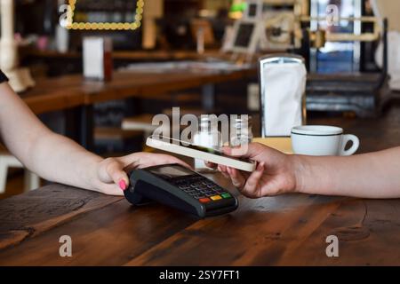 Person, die mit Mobiltelefon in einem Restaurant oder Restaurant bezahlt, Hände des Servers mit Zahlungsterminal und Kunden Stockfoto