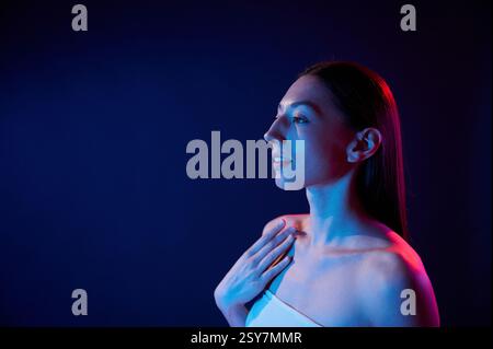 Seitenansicht. Porträt einer jungen Frau, die drinnen in Neonlicht ist. Stockfoto