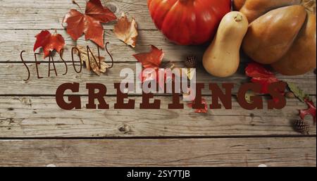 Seasons Greetings Textbild über Herbstblättern, Kürbissen und hölzernem Hintergrund Stockfoto