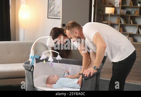 Ich sehe den Jungen in der Wiege an. Nettes Paar, das sich um das Neugeborene im Haus kümmert. Stockfoto