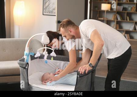 Ich sehe den Jungen in der Wiege an. Nettes Paar, das sich um das Neugeborene im Haus kümmert. Stockfoto