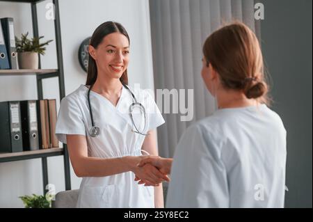 Ein junger Arzt im weißen Mantel ist mit einer Patientin im Büro. Stockfoto