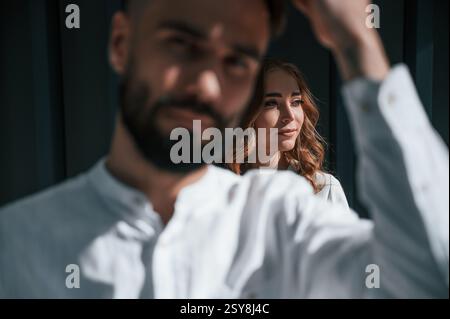 Der Mann steht vor der Frau. Das schöne junge Paar steht zusammen vor dunkelgrünem Hintergrund. Stockfoto