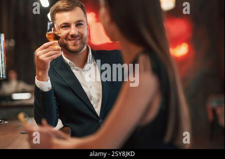 Lächelt, redet miteinander. Mann und Frau sitzen an der Bar mit einem Drink. Stockfoto
