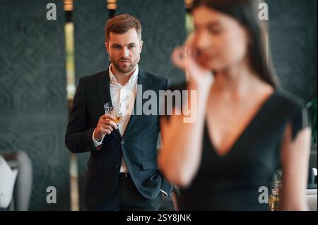 Ein Mann in schwarzem Anzug ist wütend auf eine Frau, die steht und weint. Stockfoto