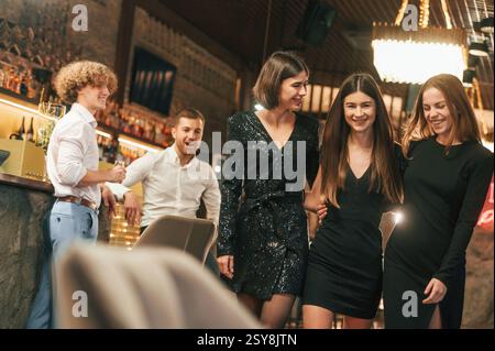 Der Mann schaut auf den Rücken der Frau. Eine Gruppe von Menschen in wunderschönen eleganten Kleidern feiert Neujahr. Stockfoto