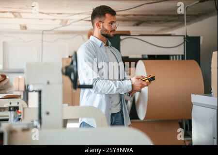 Haltesteuerung der Druckmaschine. Polygraf-Arbeiter in weißer Kleidung ist drinnen. Stockfoto