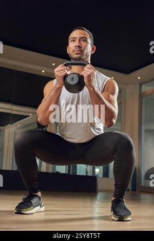 Workout, Squat und Kettlebell mit Mann im Fitnessstudio für Bewegung, Muskel und Gesundheit. Fitnesskurs, Gewichte und Sportzentrum mit männlichem Training in Stockfoto