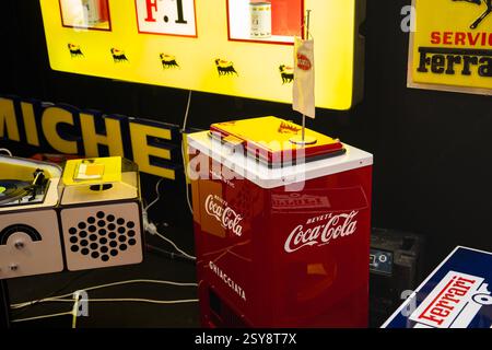Vintage-Coca-Cola-Automat, umgeben von Retro-Dekor in einem lebhaften Ausstellungsraum Stockfoto