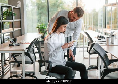 Zeigt etwas auf dem Smartphone an. Mann und Frau arbeiten im modernen Büro zusammen. Stockfoto