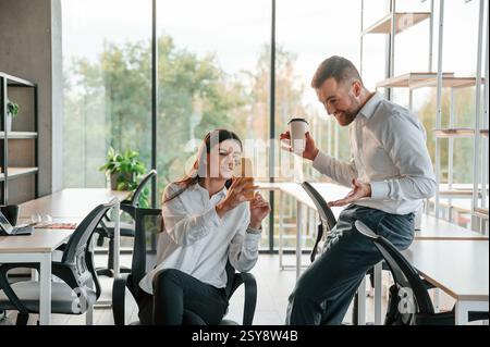 Eine Pause machen, reden, mit dem Smartphone. Mann und Frau arbeiten im modernen Büro zusammen. Stockfoto