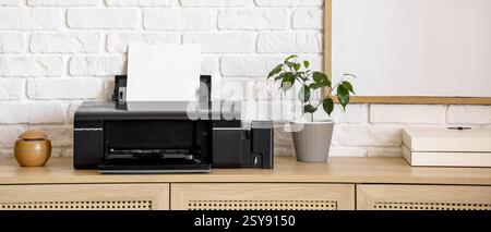 Moderner Drucker auf Kommode in der Nähe der weißen Ziegelwand im Büro Stockfoto