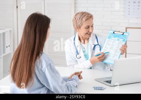 Glückliche reife Ärztin, die dem Patienten in der Klinik Testergebnisse zeigt Stockfoto