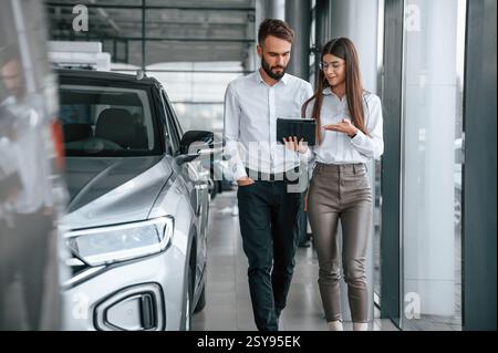 Ein Geschäftsgespräch führen. Mann mit Frau in weißer Kleidung ist zusammen im Autohaus. Stockfoto