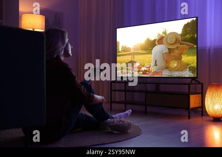 Frau, die nachts auf dem Fernseher im Zimmer einen Film ansieht Stockfoto