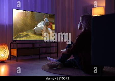 Frau, die nachts auf dem Fernseher im Zimmer einen Film ansieht Stockfoto