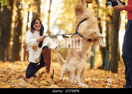 Die Frau ist mit Hund, der auf den Beinen steht, neben dem Mann mit Kamera. Stockfoto