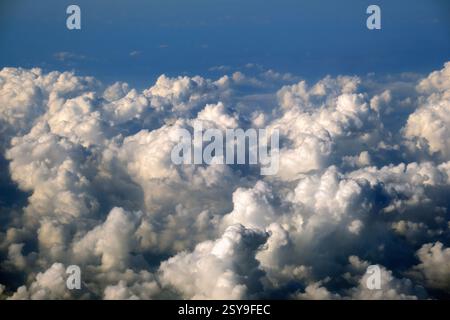 Luftaufnahme aus dem Flugzeugfenster in großer Höhe von dichten, geschwollenen Kumuluswolken, die fliegen Stockfoto