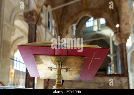 Offene Bibel auf einem Rednerpult in einer Kirche mit verschwommenem Hintergrund und sanftem Licht aus den Fenstern Stockfoto