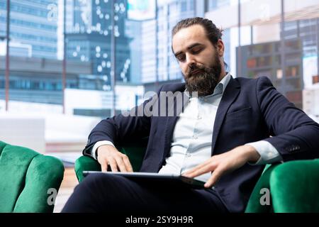 Der ehrgeizige Marktführer in einem luxuriösen Hauptsitz plant Geschäftsausweitung, ausgewogene Gewinnberichte und die Bewertung von Markttrends auf seinem Notebook. Datengesteuerte Entscheidungen für den Unternehmenserfolg. Stockfoto