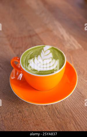 Schöner Matcha Latte mit kompliziertem Blattdesign in lebendiger Tasse Stockfoto