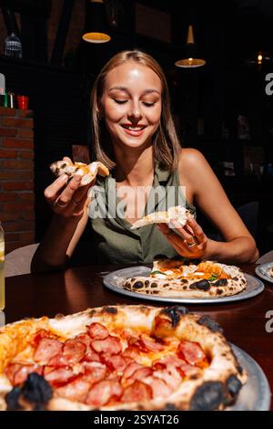 Eine Person genießt Scheiben Margherita und Peperoni Pizza gepaart mit einem erfrischenden Glas Limonade im Haus. Die Szene zeigt ein gemütliches und Appet Stockfoto