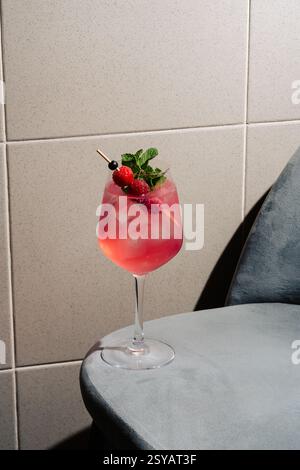 Ein erfrischendes Beere Gin Tonic garniert mit Himbeeren, Johannisbeeren und Minze. Serviert in einem transparenten Becher mit Eiswürfeln, ideal für einen lebendigen und aufgeweckten Kaffee Stockfoto