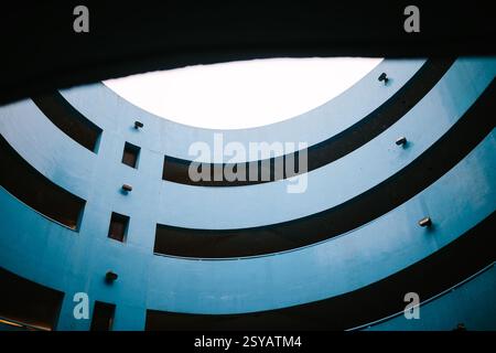 Architekturfoto eines blauen Parkhauses mit mehreren geschwungenen Schichten und einer dynamischen Perspektive. Das Bild erfasst den fließenden lin Stockfoto